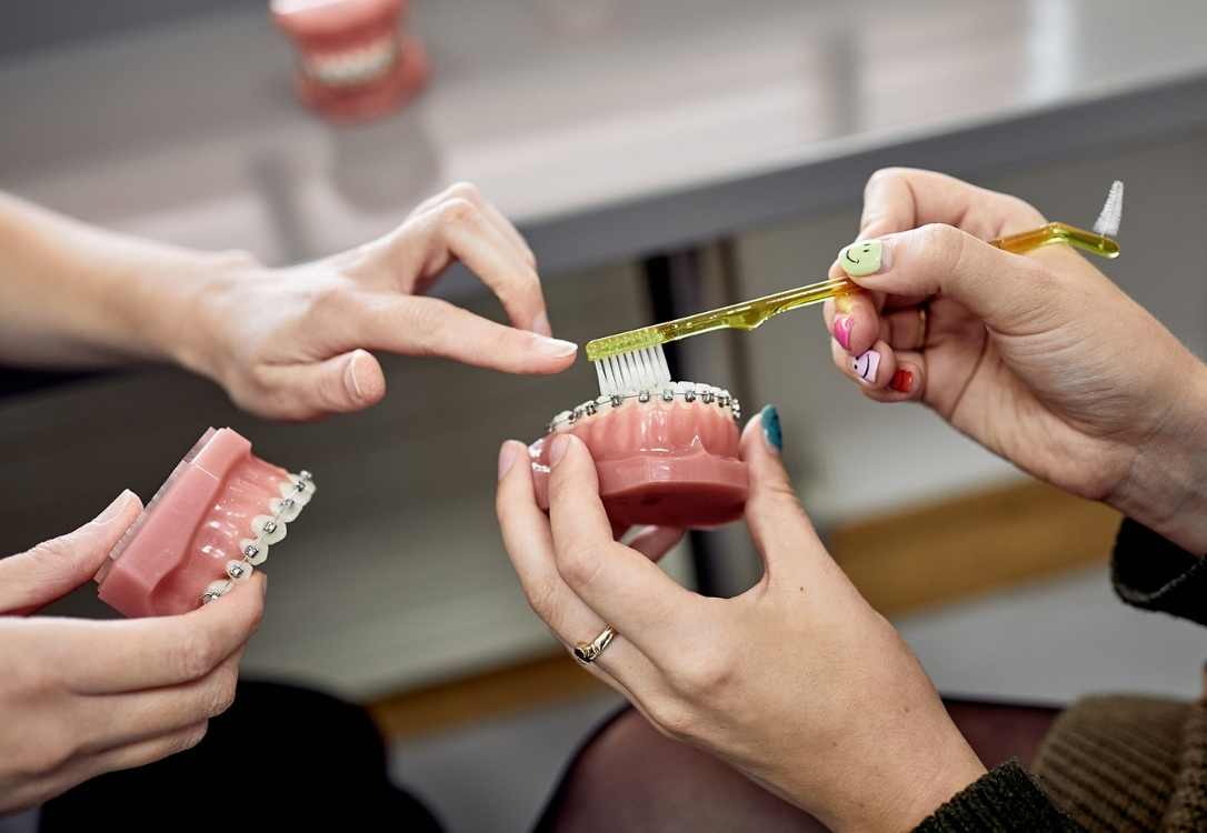 Orthodontist showing how to care for braces